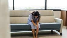 Photo of a woman in a hospital gown with eyes downcast, to illustrate article 