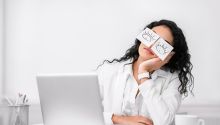 What Does the Bible Say About Quiet Quitting? Photo illustration of woman at work with paper open eyes taped over her eyes.